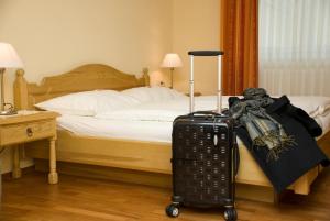 una camera d'albergo con un letto e una valigia di Gasthof Manner a Perg