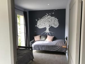 1 dormitorio con 1 cama con una plantilla de árboles en la pared en Pays des Senteurs, en Saint-Ferréol-Trente-Pas