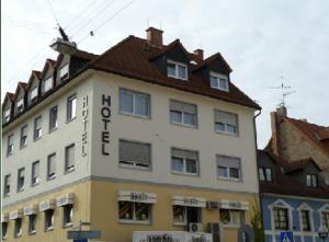 un grand bâtiment blanc avec un toit marron dans l'établissement Hotel Domino, à Hanau