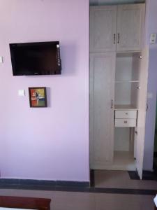 Lambada Holiday Resort Mombasa في متوابا: غرفة ذات جدار أبيض مع تلفزيون بشاشة مسطحة