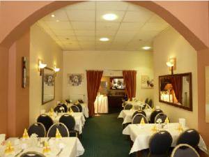 un comedor con mesas blancas y sillas negras en Hotel Domino, en Hanau am Main