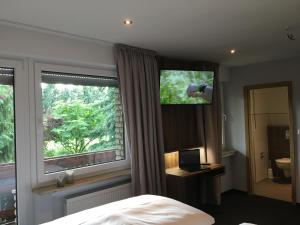 a bedroom with a bed and a window with a television at Landhaus Hotel Göke in Hövelhof