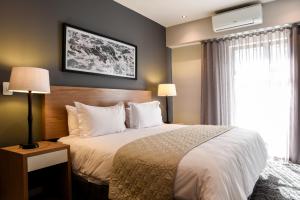 um quarto de hotel com uma cama e uma janela em The Residency Jellicoe em Joanesburgo