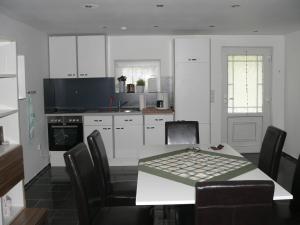 a kitchen with a table and chairs and a kitchen with white cabinets at Ferienhaus Zum grünen Holz in Zetel