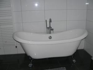 a white bath tub with a faucet in a bathroom at Ferienhaus Zum grünen Holz in Zetel +63 photos