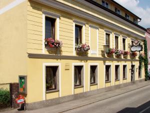 un edificio amarillo con macetas de flores a un lado. en Gasthof Manner, en Perg