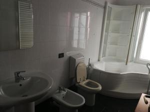a white bathroom with a sink and a toilet at Grado Exclusive Apartment in Grado