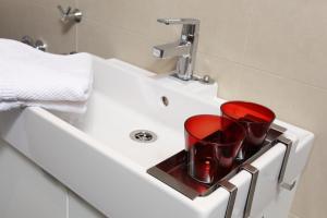 un lavabo con 2 tazas rojas en una bandeja en Hoheschule Apartment Courbette, en Viena