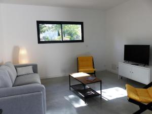 a living room with a couch and a tv at Villa piscine Sud France in Verzeille