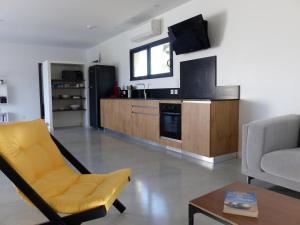a living room with a yellow chair and a kitchen at Villa piscine Sud France in Verzeille