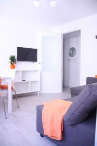 a living room with a blue couch and a tv at Apartamento Orange Triana centro in Seville