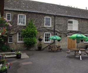 a stone building with tables and umbrellas in front of it at The Bell Inn in Oxford