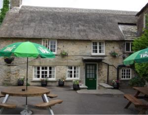 a stone building with two tables and an umbrella at The Bell Inn in Oxford