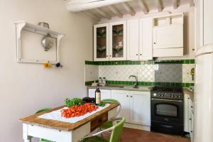 una cucina con armadi bianchi e un tavolo con verdure di Il Nido di Margherita a San Giovanni Valdarno