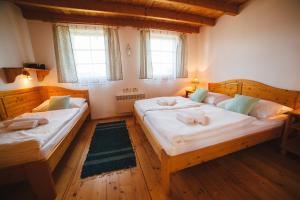 two beds in a room with wooden floors and windows at Chata 107 Tatralandia Village in Liptovský Mikuláš