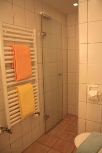 ein Badezimmer mit einem orangenen Handtuch und einer Dusche in der Unterkunft Feriendomizil am Kurplatz in Norderney
