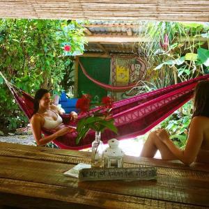 due donne sedute su un'amaca in giardino di Hostel Mariposas a Sámara