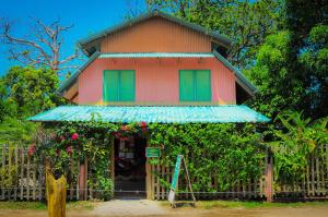 une petite maison avec des portes vertes et une clôture dans l'établissement Hostel Mariposas, à Sámara