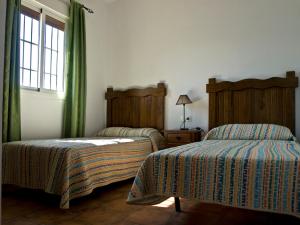 コニル・デ・ラ・フロンテーラにあるCasa Marinasの緑のカーテンと窓が備わる客室で、ベッド2台が備わります。