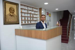 un hombre parado detrás de un mostrador en una farmacia en Hotel Altuğ, en Isparta