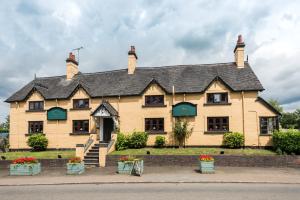a large yellow house with a black roof at Golden Lion Hotel in Rugby