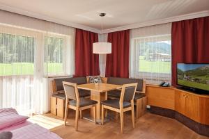 ein Wohnzimmer mit einem Tisch und einem TV in der Unterkunft Apartments Neue Post in Filzmoos