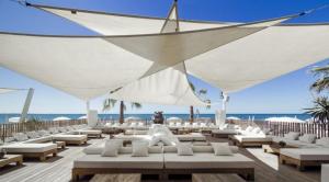 una playa con sombrillas y sillas blancas y el océano en Appartement du golf, en La Grande-Motte
