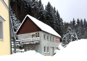un edificio cubierto de nieve con árboles en el fondo en Wohnen beim Kunsthandwerker, en Neuhausen