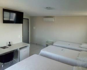 um quarto com 2 camas e uma secretária com um computador em COBH Hotel em Caruaru