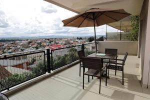 Un balcón con una mesa y sillas y una sombrilla. en Atlantis, en Antananarivo