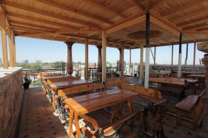 une rangée de tables et de bancs en bois dans un restaurant dans l'établissement Furkat Guest House, à Samarcande