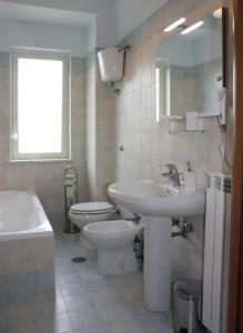 een badkamer met een wastafel, een toilet en een spiegel bij Libro di Sogni - B&B Letterario in Casertavecchia