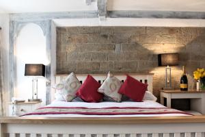 1 dormitorio con 1 cama con almohadas rojas y blancas en Healds Hall Hotel en Cleckheaton