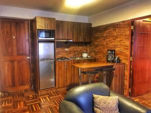a kitchen with wooden cabinets and a couch in a room at Cusco Inloft en pareja in Cusco