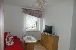 a living room with a couch and a tv and a window at Pension Irmisch in Aue