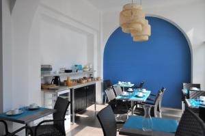 ein Restaurant mit blauen Wänden, Tischen und Stühlen in der Unterkunft Hôtel de la Mer in Valras-Plage