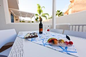 a table with a bottle of wine and a plate of food at Claudia Blu Mar con piscina e Wi-Fi in San Vito lo Capo