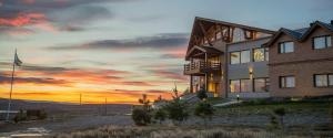 a house on a hill with a sunset in the background at Terraza Coirones Hotel in El Calafate