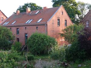 ein altes rotes Backsteingebäude mit einem Dach in der Unterkunft Botanische Botschaft in Strodehne