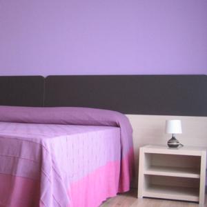 una camera con letto viola e tavolo con lampada di B&B 5 Sensi a Belpasso