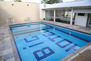 a swimming pool with blue water in front of a house at Big Executive Hotel in Araguari