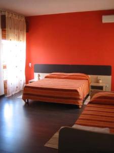 una camera da letto con due letti e una parete rossa di B&B 5 Sensi a Belpasso