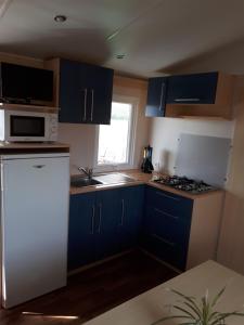 a kitchen with blue cabinets and a white refrigerator at Mobil home in El Palmar