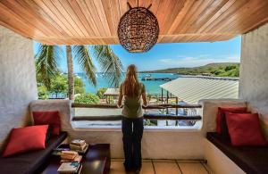 a woman looking out of a window at the water at Casa Opuntia in Puerto Baquerizo Moreno