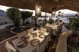 a restaurant with white tables and chairs with a view of the water at Casa Opuntia in Puerto Baquerizo Moreno +19 photos