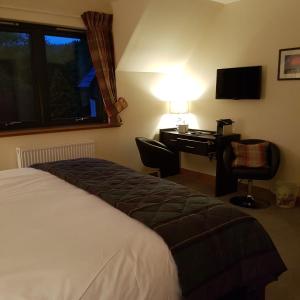 a hotel room with a bed and a desk with a computer at Kilmichael House in Drumnadrochit