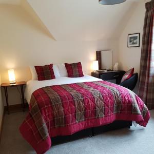 a bedroom with a large bed and a chair at Kilmichael House in Drumnadrochit
