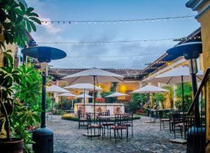 an outdoor patio with tables and chairs with umbrellas at Hotel Convento Santa Catalina by AHS in Antigua Guatemala