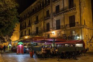 un grupo de personas sentadas en mesas fuera de un edificio en Vittorio Emanuele Appartamenti, en Palermo 2 fotos más