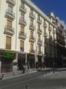 a large white building with balconies on a street at Hostal Triana in Madrid